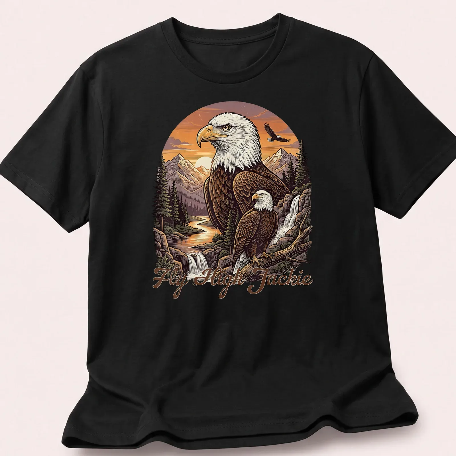 Illustration of a Bald Eagle flying over a mountain scene with the text Fly High Jackie — printed on a unisex t-shirt