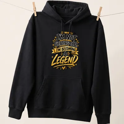 Bold typography t-shirt with the text I'm Not Getting Old, I'm Becoming a Legend in black, gold, and white. — printed on a unisex hoodie