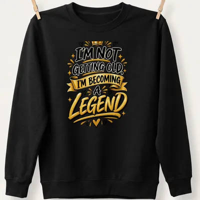 Bold typography t-shirt with the text I'm Not Getting Old, I'm Becoming a Legend in black, gold, and white. — printed on a unisex sweatshirt