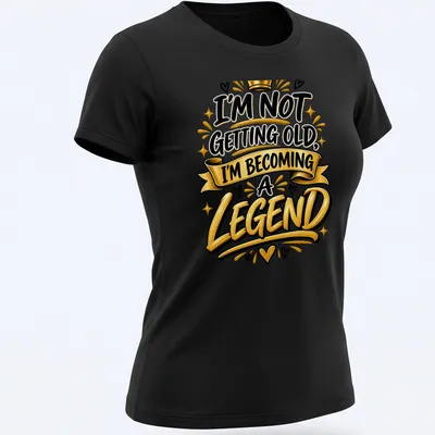 Bold typography t-shirt with the text I'm Not Getting Old, I'm Becoming a Legend in black, gold, and white. — printed on a women's shirt