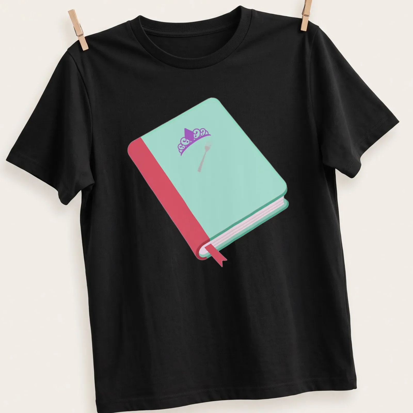 Whimsical illustration of a book with a crown and fork in flat design — printed on a unisex t-shirt