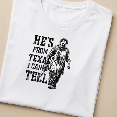 Vintage horror tee featuring a chainsaw character with the text 'He's from Texas I can tell' — printed on a women's shirt