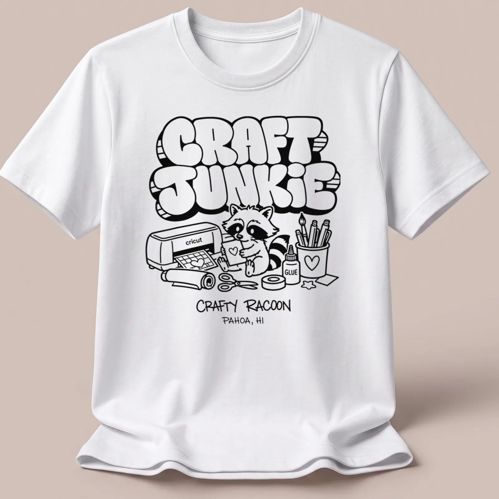 Cartoon raccoon graphic with text 'CRAFT JUNKIE CRAFTY RACOON PAHOA, HI' in black and white — printed on a unisex t-shirt