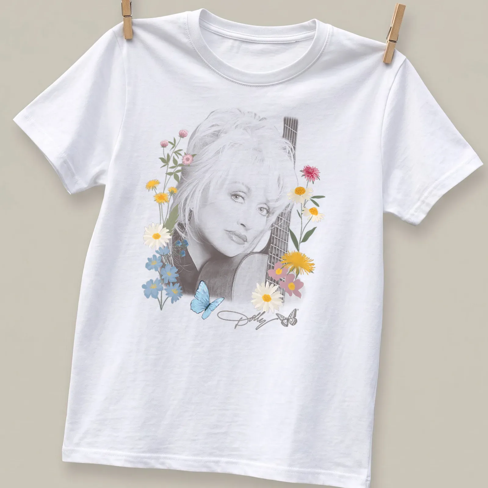 Portrait of Dolly Parton surrounded by flowers and butterflies in vibrant colors — printed on a unisex t-shirt