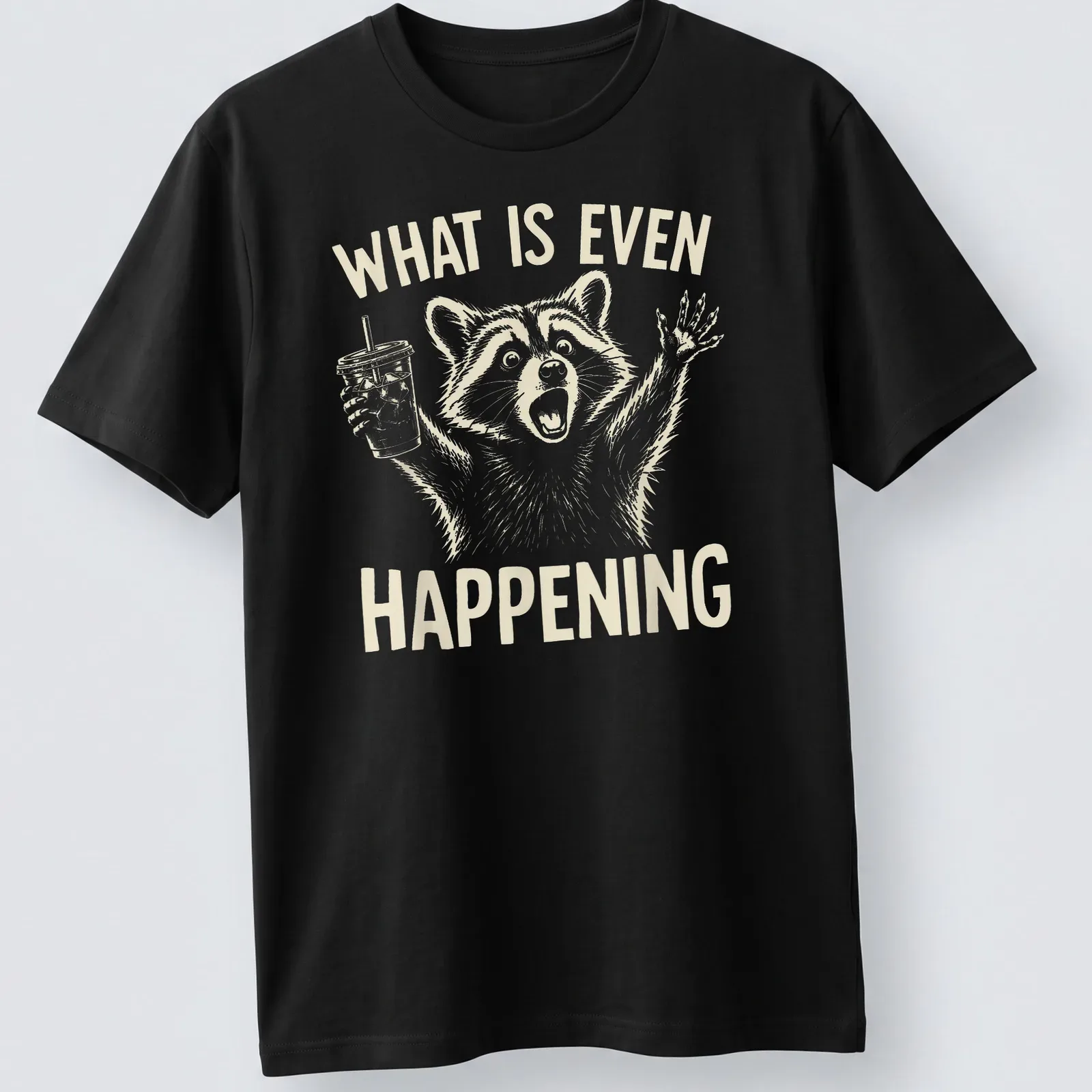 Light beige raccoon holding iced coffee with line-art style and humorous text. — printed on a unisex t-shirt