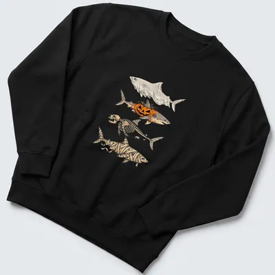 Illustrative t-shirt featuring a shark skeleton, pumpkin, and mummy elements for Halloween — printed on a unisex sweatshirt