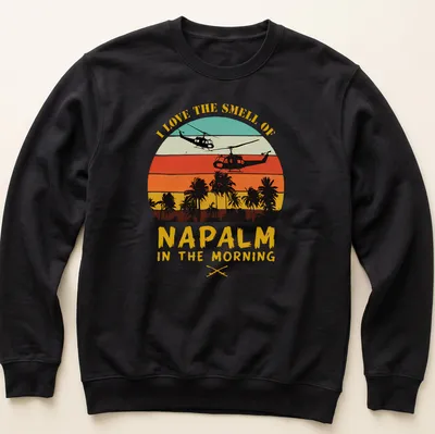 Retro sunset design with helicopters and bold text about napalm smell — printed on a unisex sweatshirt