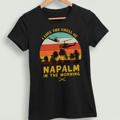 Retro sunset design with helicopters and bold text about napalm smell — printed on a women's shirt