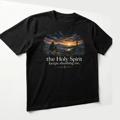 A serene illustration of a man on rocks at sunset with cross and text about the Holy Spirit — printed on a unisex t-shirt (angled view)
