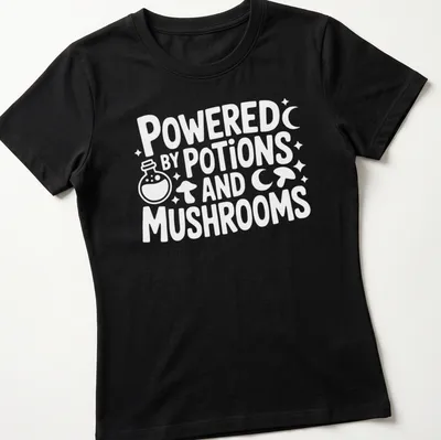 Whimsical print featuring mushrooms and potions with the text 'Powered By Potions And Mushrooms' — printed on a women's shirt