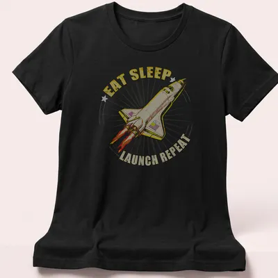 Vintage-style tee featuring a rocket and the text 'EAT SLEEP LAUNCH REPEAT' — printed on a women's shirt