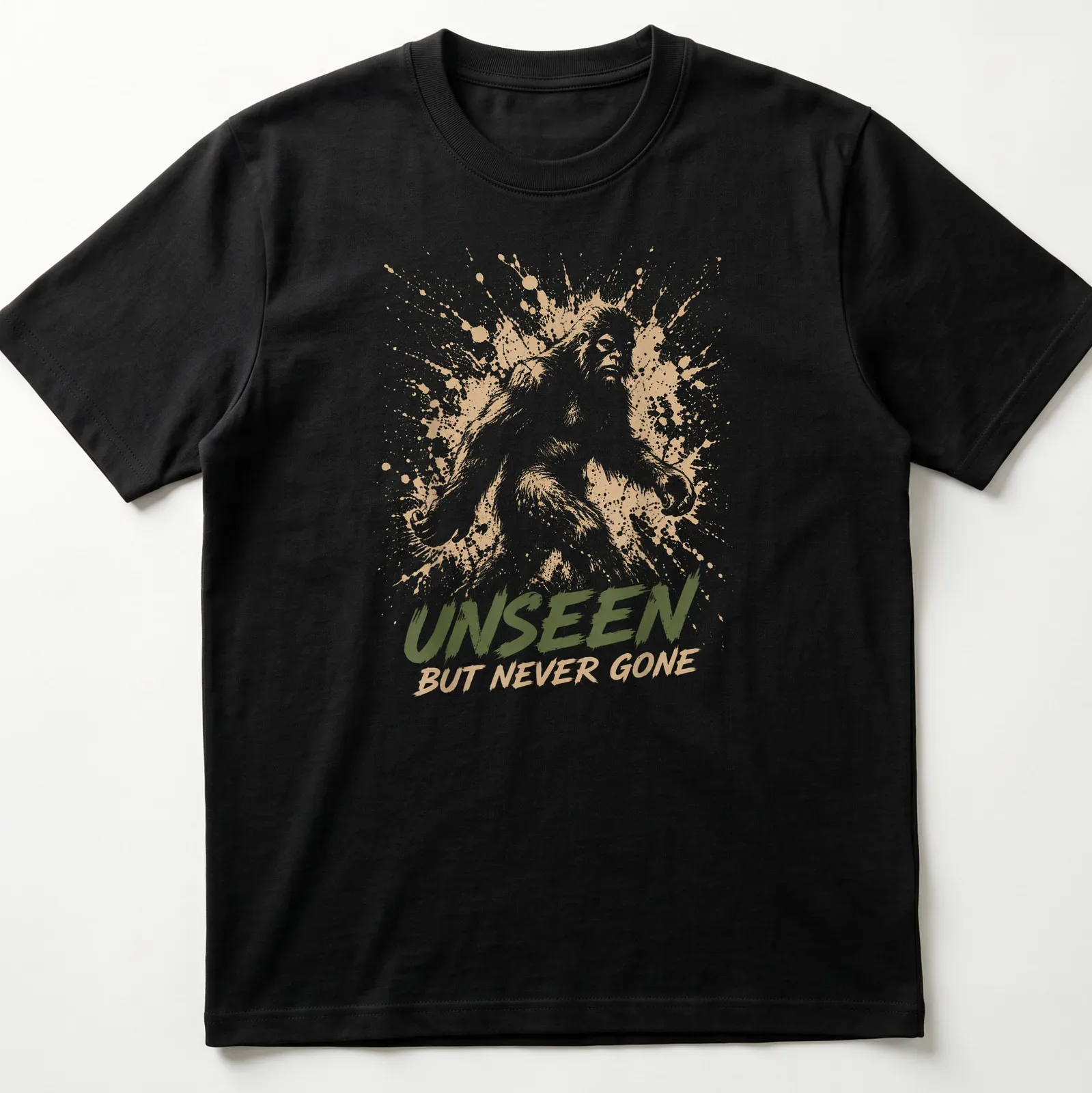 Sasquatch silhouette with splash art style and text 'Unseen But Never Gone.' — printed on a unisex t-shirt