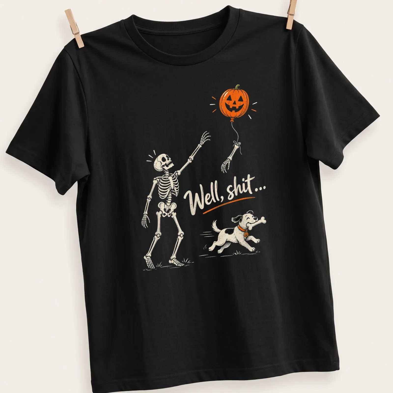 Playful cartoon skeleton dog chasing a pumpkin balloon with humorous text — printed on a unisex t-shirt