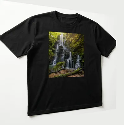 Photographic print of a waterfall surrounded by lush greenery in earthy tones — printed on a unisex t-shirt (angled view)