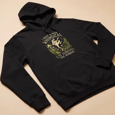 Whimsical illustration of a frog with the text 'I Must Remain Whimsical To Survive The Horror' — printed on a unisex hoodie